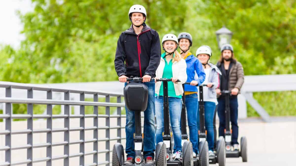 20 Ultimate No-Nos of Cruise Packing—Learn What's Banned 9 A group of five cheerful adults wearing helmets ride segways in a line along a park pathway, with trees and railings visible in the background.