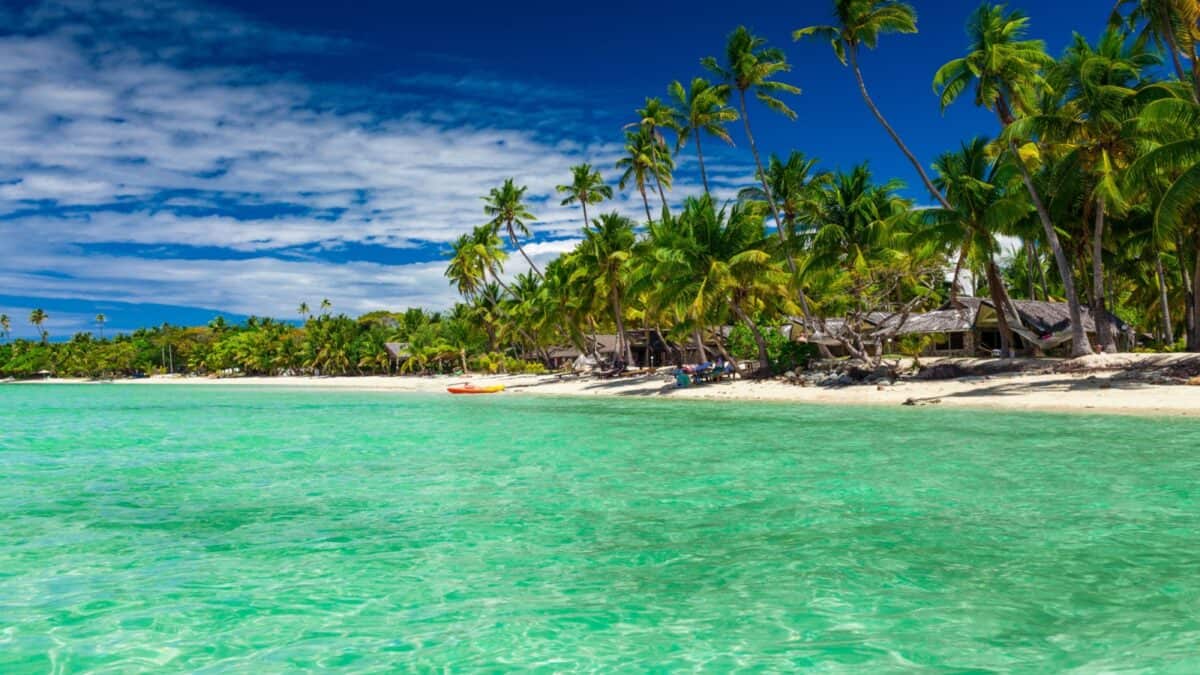 16 Survivor Locations that Would Actually Make Super Cool Vacation Destinations 11 A beach in Fiji with clear waters surrounded by tall trees.