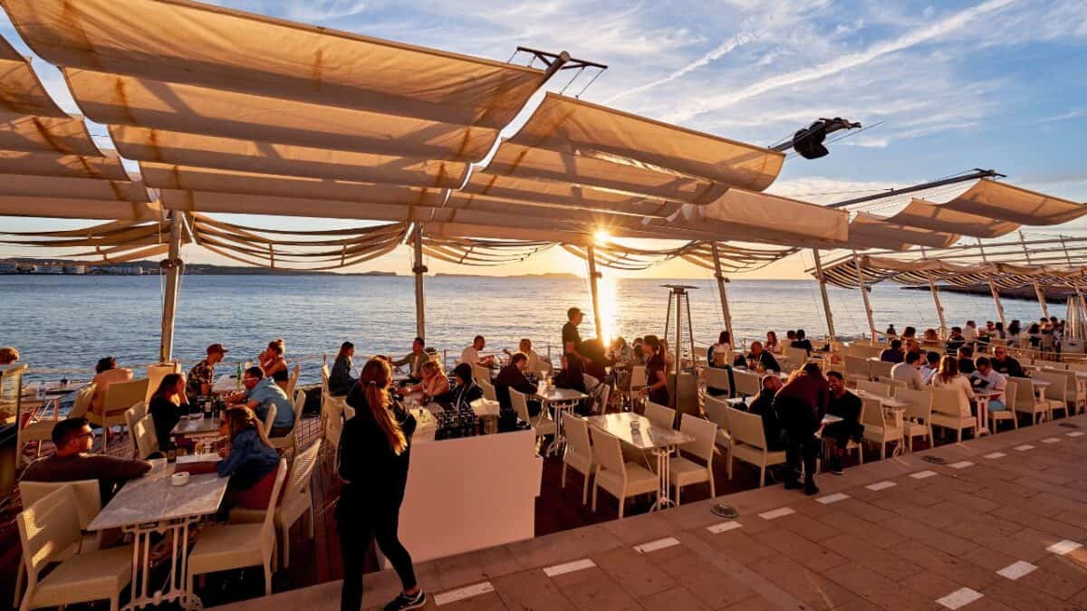 a group of people sitting at tables and chairs on a dock