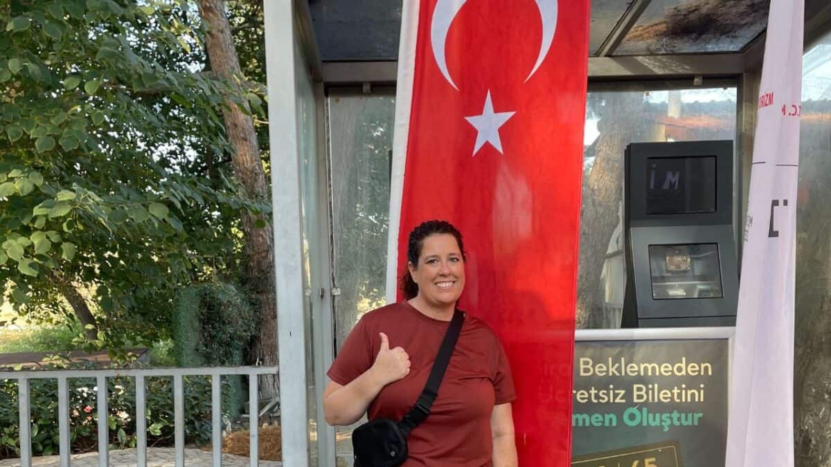 20 Best Places For Solo Female Travelers 26 Person smiling with thumbs up in front of a Turkish flag at a kiosk.